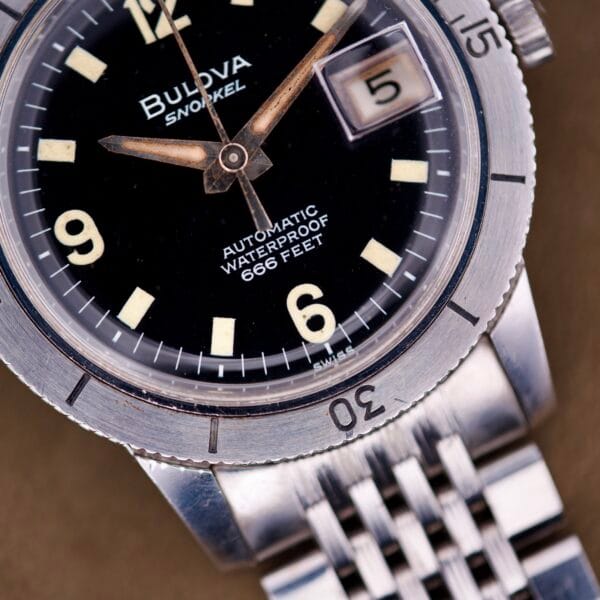 Close-up of the Bulova Snorkel Automatic Devil Diver Ref. 386 Black Dial, showcasing its black dial, hands, and metal bracelet.