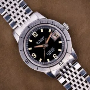 Close-up of a Bulova Snorkel Automatic Devil Diver Ref. 386 with black dial and silver metal band, displayed on a brown surface.