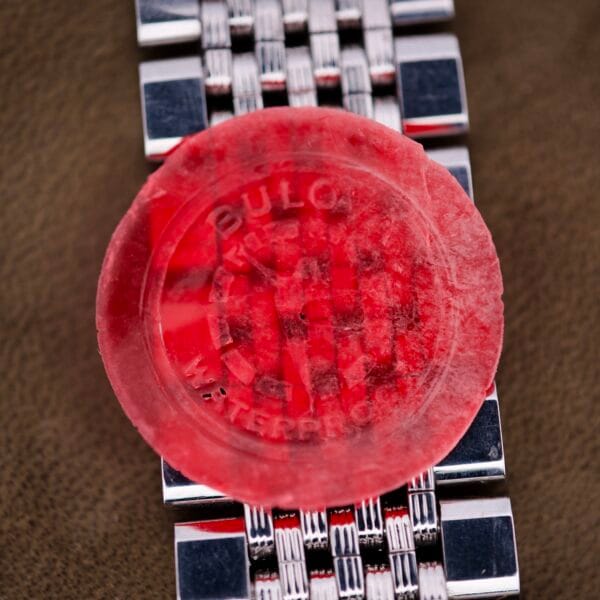 A red wax seal marked "Bulova Waterproof" rests on the silver band of a Bulova Snorkel Automatic Devil Diver Ref. 386 with a black dial, displayed on a brown surface.
