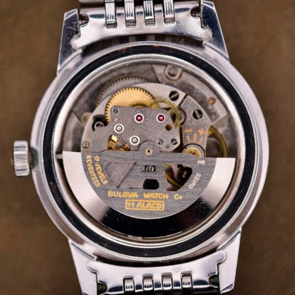 Close-up of the Bulova Snorkel Automatic Devil Diver Ref. 386, showcasing its exposed mechanical movement and visible gears behind the striking black dial, a testament to its expert craftsmanship.