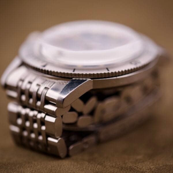 Close-up of a Bulova Snorkel Automatic Devil Diver Ref. 386 wristwatch with black dial and metal band, shown on its side against a brown background.