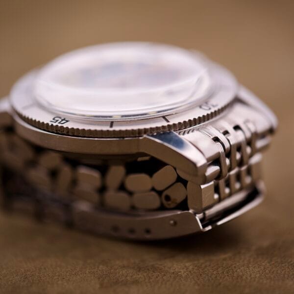 Close-up of a Bulova Snorkel Automatic Devil Diver Ref. 386 with a metal bracelet, highlighting the bezel and striking black dial, displayed on a brown surface.