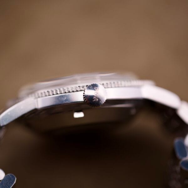 Close-up side view of the Bulova Snorkel Automatic Devil Diver Ref. 386 Black Dial's crown and case, set against a blurred brown background.