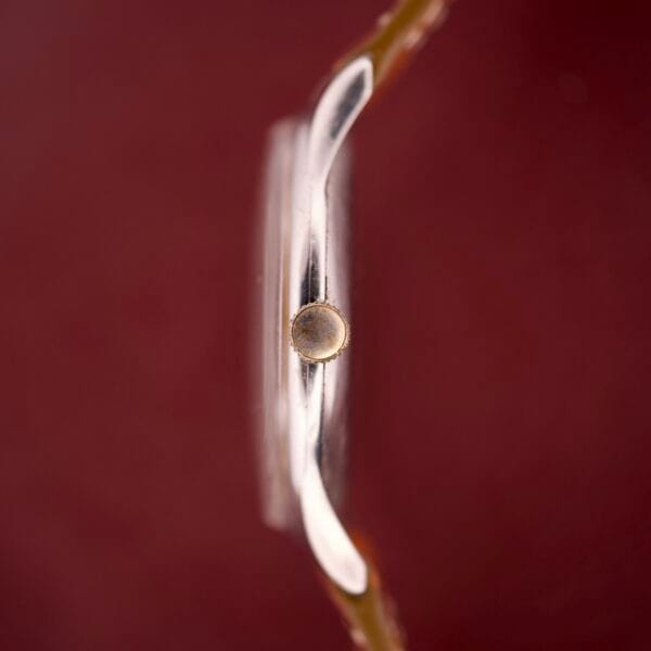 Side view of the Zenith Caltrava Jumbo with Arabic numerals and subseconds, featuring a round crown and stainless steel case, set against a plain burgundy background.