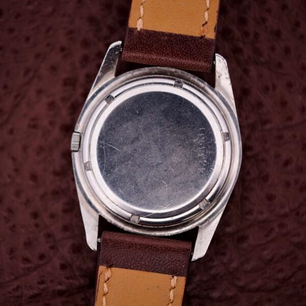 The back of an Eterna-Matic Chronometer Automatic Date Tropic Dial 21 Jewels with brown leather straps rests on a textured brown surface.