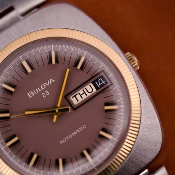 Close-up of the Bulova Day/Date 23 Jewels Automatic Two Tone Cushion Case Fluted Bezel watch, showing THU and the 14th on its dial.