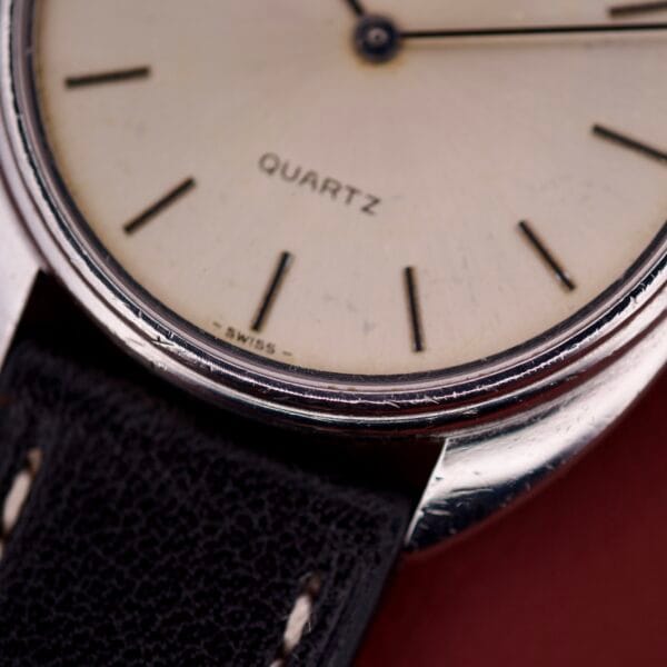 Close-up of a Universal Geneve Quartz Ref. 874 108 wristwatch, featuring a black leather strap, stainless steel cushion case, and "SWISS" on the dial.