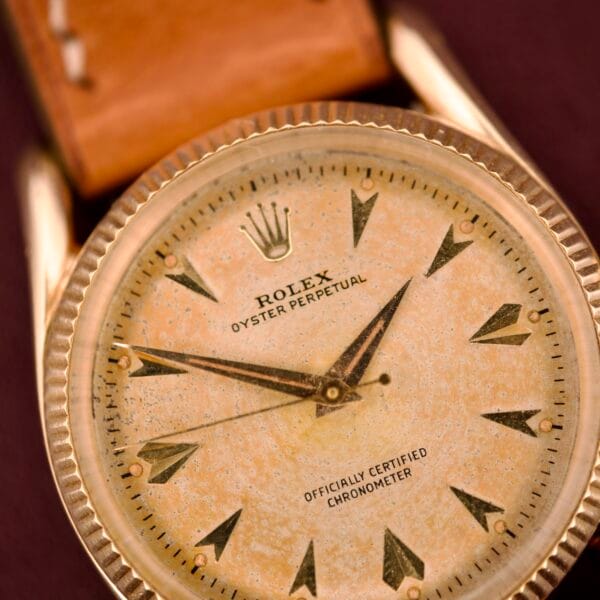Close-up of a vintage Rolex Oyster Perpetual 'Bombay' Ref. 6593 with a 14K yellow gold case and brown leather strap, exuding timeless elegance and classic sophistication.