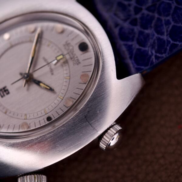 Close-up of a Lecoultre Automatic Memovox Reveil "Egg" Ref. 3072-916 with Cal. 916, featuring a silver case, blue strap, watch face, side crown, and distinctive Memovox details.
