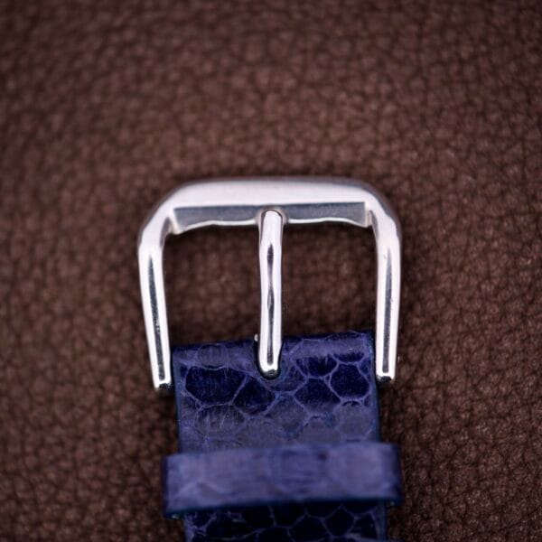 Silver buckle on a blue patterned strap, set against a textured brown background—this Lecoultre Automatic Memovox Reveil "Egg" Ref. 3072-916 Cal. 916 channels an elegant nod to classic style.