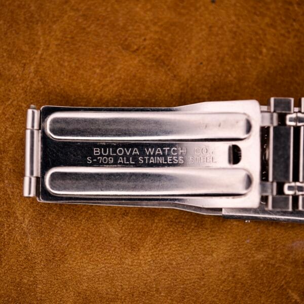 Close-up of a Bulova stainless steel watch clasp engraved with BULOVA WATCH CO. S-709 ALL STAINLESS STEEL, as seen on vintage Bulova Accutron Astronaut 214 GMT 24 Hour Bezel Black Dial models.