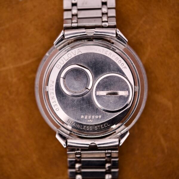 Back of a Bulova Accutron Astronaut 214 GMT 24 Hour Bezel Black Dial wristwatch, showing stainless steel case, waterproof marking, visible battery compartments, and elements of its iconic design.