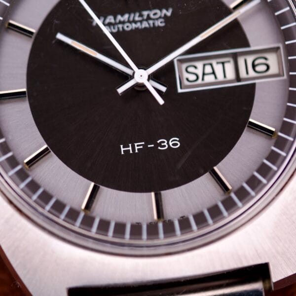 Close-up of a Hamilton Automatic HF-36 Day-Date Hi-Beat Cal. 631 watch face, highlighting its precision movement and clear day-date display showing SAT 16.