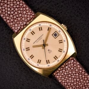 The Girard Perregaux Electronic Ref. 9280 6H Large Cushion Case features a gold finish, brown strap, beige dial, black hour markers, and a date window at 3 o’clock—an iconic design.