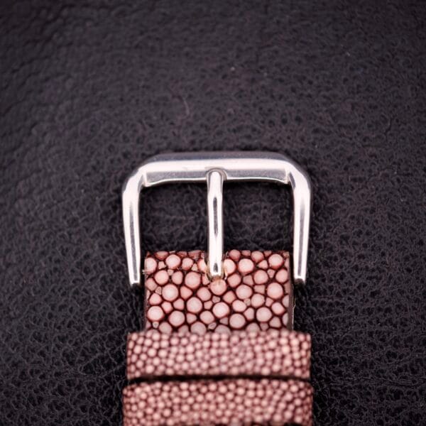 Close-up of a silver Girard Perregaux buckle on a textured brown leather strap, set against black—a refined detail from the Electronic Ref. 9280 6H Large Cushion Case.