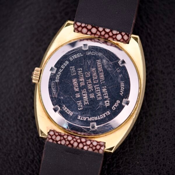 Close-up of a Girard Perregaux Electronic Ref. 9280 6H Large Cushion Case gold wristwatch back, featuring an engraved inscription and a black leather strap.