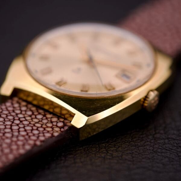 Close-up of a Girard Perregaux Electronic Ref. 9280 6H Large Cushion Case gold wristwatch with a brown textured leather strap, shown on a dark surface.