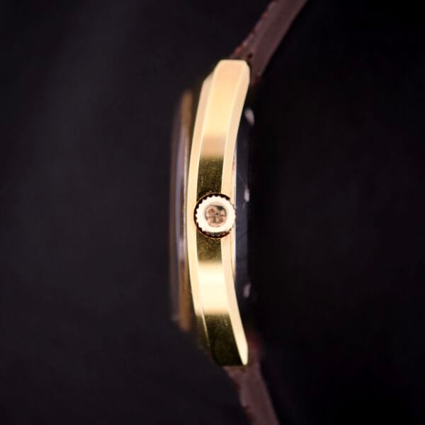 Side view of a Girard Perregaux Electronic Ref. 9280 6H Large Cushion Case gold watch with crown and brown leather strap, displayed against a black background.