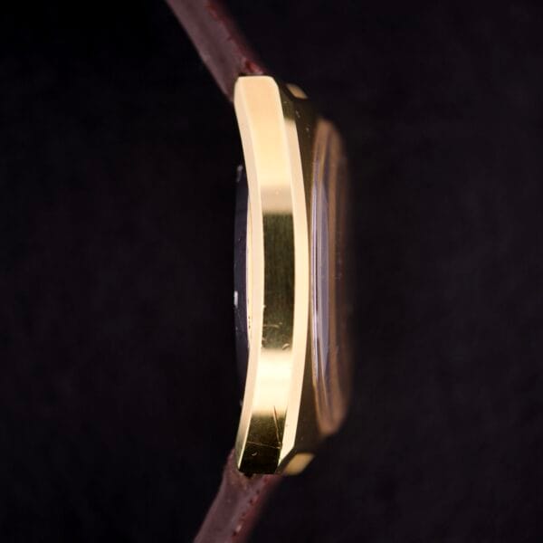 Side view of a Girard Perregaux Electronic Ref. 9280 6H Large Cushion Case gold wristwatch with a brown leather strap, set against a dark background.