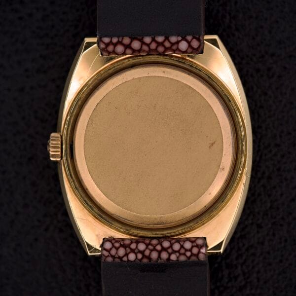 A close-up of the back of a Girard Perregaux Electronic Ref. 9280 6H Large Cushion Case gold wristwatch with a black and brown textured strap.
