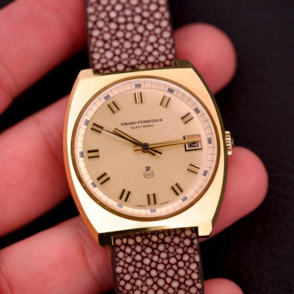 Girard Perregaux Electronic Ref. 9280 6H wristwatch with a large cushion case, brown textured strap, beige dial, and date display.