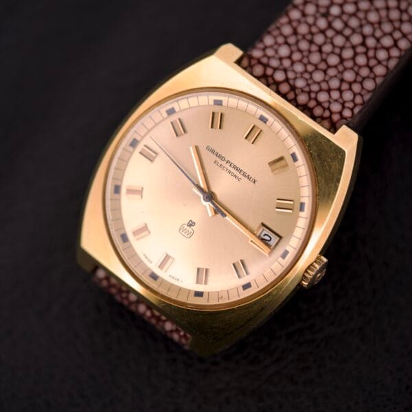 Girard Perregaux Electronic Ref. 9280 6H Large Cushion Case wristwatch with brown strap on a dark textured surface, displaying the time at 7:10.