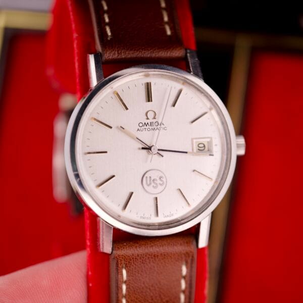 A close-up of an Omega Automatic Seamaster Ref. 166.020 For "U.S. Steel" with Cal. 1010 movement, full set, featuring a brown leather band and date window.