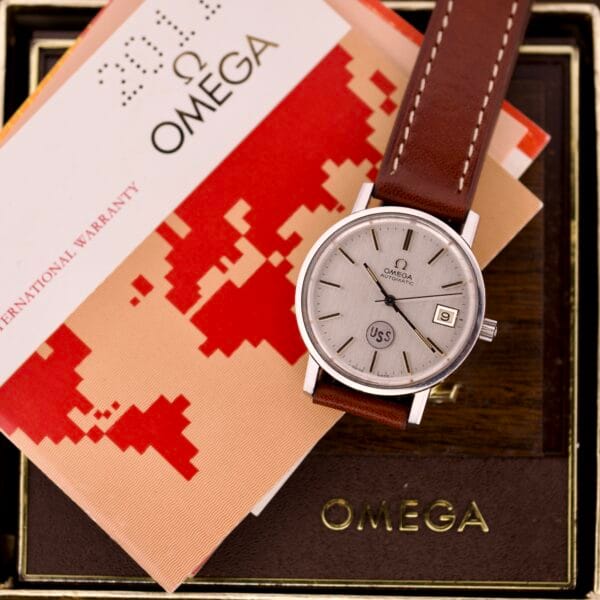 An Omega Automatic Seamaster Ref. 166.020 For "U.S. Steel" Cal. 1010 Full Set wristwatch with a brown leather strap, displayed on Omega boxes and warranty cards.