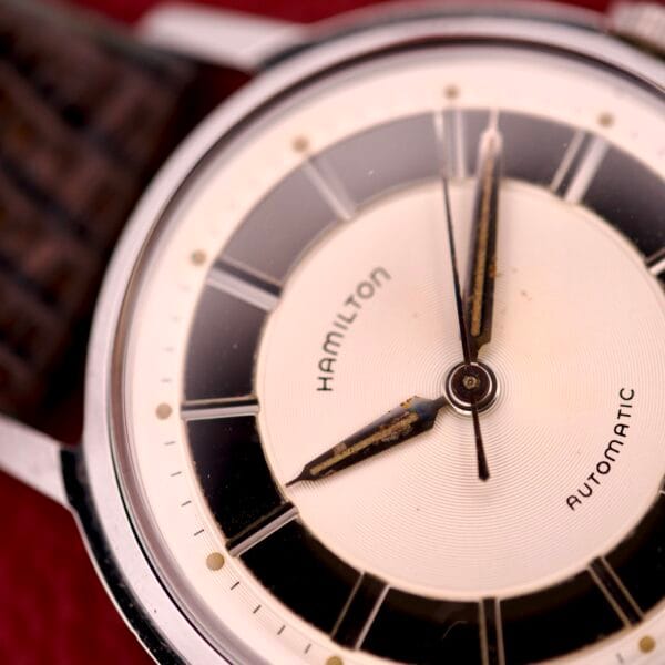 Close-up of a vintage Hamilton Thin-o-matic T-500 Caliber 666 Automatic Micro-Rotor watch, highlighting the brand name and time at 11:57, and showcasing its classic micro-rotor movement.