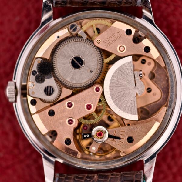 Close-up of a Hamilton Thin-o-matic T-500 Caliber 666 automatic micro-rotor movement with visible gears and components set against a red background.