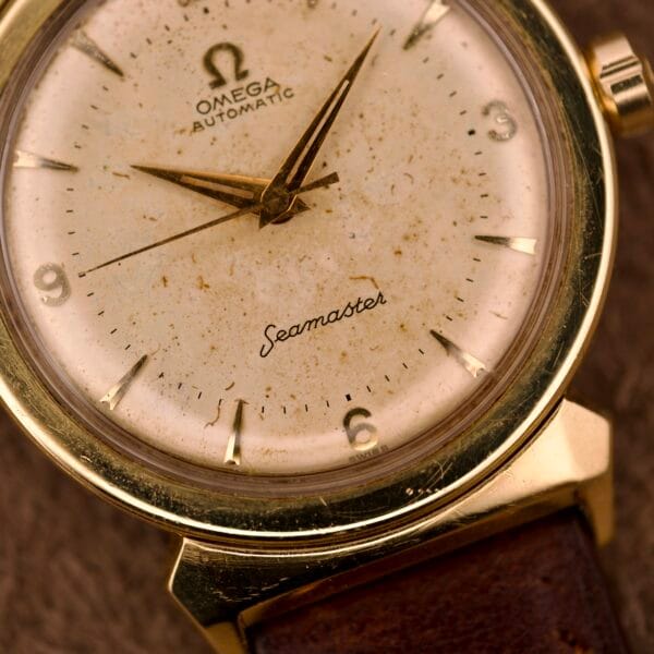 Close-up of an Omega Automatic Seamaster Ref. 14363 in 14k gold-capped Bull Horn Lugs, featuring a worn speckled dial and classic leather strap.