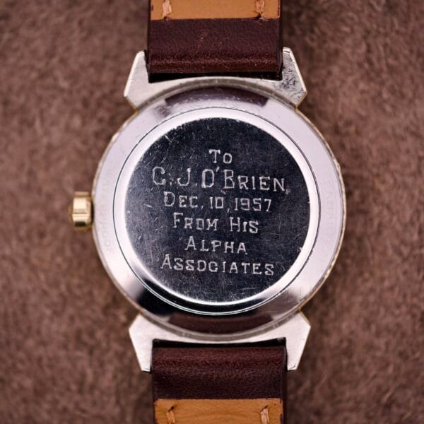 Back of an Omega Automatic Seamaster Ref. 14363 14k Gold Capped Bull Horn Lugs, engraved with a dedication to C.J. OBrien from Alpha Associates, dated Dec. 10, 1957.