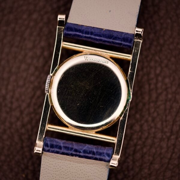 A close-up of a Longines Mainliner Art Deco Drivers Watch Manual Wind Cal. 8L, featuring a W&A GOLD FILLED back and a blue and white leather strap.