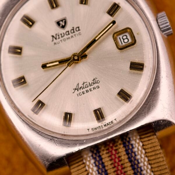 Close-up of the Nivada Automatic Antarctic Iceberg Date Ref. 4297, showcasing gold hands and indices on a striking sunburst dial, with the date set to 18.