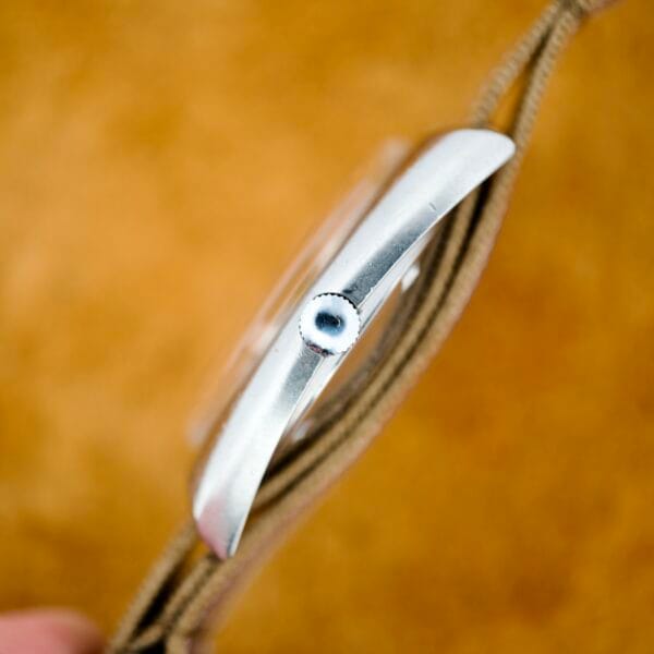 Side view of the Nivada Automatic Antarctic Iceberg Date Ref. 4297 with a brown strap and vibrant sunburst dial, shown against a blurred tan background.