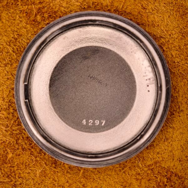 A round metal lid marked 4297, evoking the Nivada Automatic Antarctic Iceberg Date Sunburst Dial, rests on a textured brown surface.