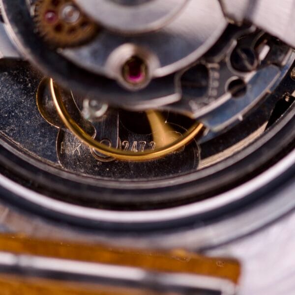 Close-up of the Nivada Automatic Antarctic Iceberg Date Ref. 4297 Sunburst Dial, highlighting engraved serial number 2472 and precise metallic gears, echoing the intricate beauty of Antarctic icebergs.