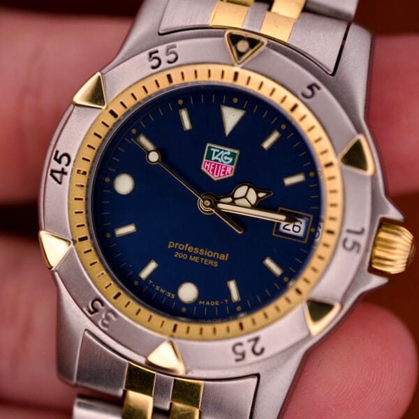 Close-up of a Tag Heuer 1500 Series Ref. WD 1221-K-20 watch, featuring a blue sunburst dial, gold accents, and a two-tone silver and gold band.