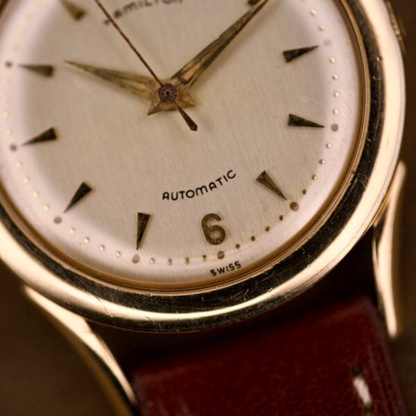 Close-up of a Hamilton Automatic Ref. K-407 wristwatch featuring a 10k gold filled case, gold markers, Cal. 661 movement, and a brown leather strap.