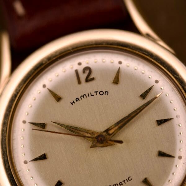 Close-up of a Hamilton Automatic Ref. K-407 wristwatch, featuring a 10k gold filled case, gold hour markers and hands, and a cream-colored face. Powered by Cal. 661 movement.