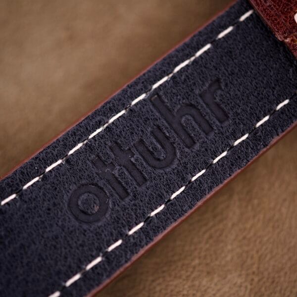 Close-up of a leather strap with "otiuhr" embossed and white stitching, complementing a Hamilton Automatic Ref. K-407 10k Gold Filled Case Cal. 661.