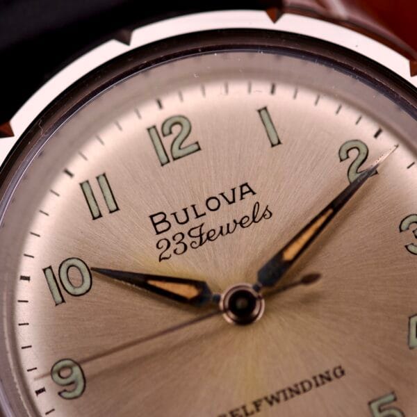 Close-up of a 1970 Bulova 23 Jewels Self-Winding Cal. 10BZAC watch, showcasing gold hands, green-tinted hour markers, and a stainless steel case.