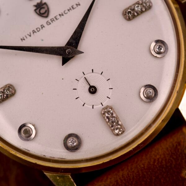Close-up of the Nivada Grenchen Manual Wind Cal. R34 with a white dial, diamond markers, and black hands, showcasing its elegant manual movement.
