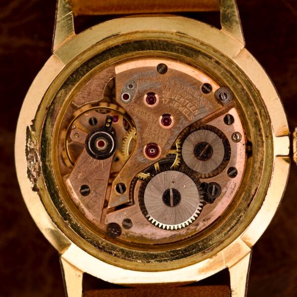 Close-up of a vintage Nivada Grenchen Manual Wind Cal. R34’s exposed mechanical movement, showcasing intricate gears and white dial with elegant diamond markers.