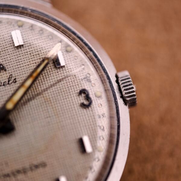 Close-up of a Bulova 30 Jewels Automatic Cal. 10COAC wristwatch, showcasing its waffle dial, stainless steel case, 3 o’clock mark, and part of the crown.