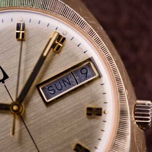 Close-up of a Bulova Accutron Turning Fork Cal. 2182 Day-Date Cushion Case wristwatch, highlighting its signature tuning fork movement and displaying Sunday the 9th.