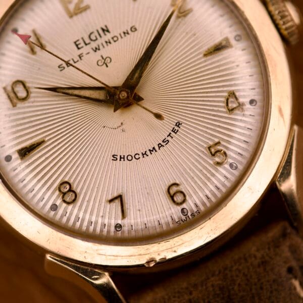 Close-up of an Elgin Automatic Shock-Master Guilloché Dial Cal. 643 watch, showcasing gold numerals and a textured guilloché dial.