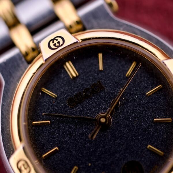 Close-up of a Gucci 9000 Ladies Watch with a black slate dial, two-tone quartz design, and iconic Gucci logo.