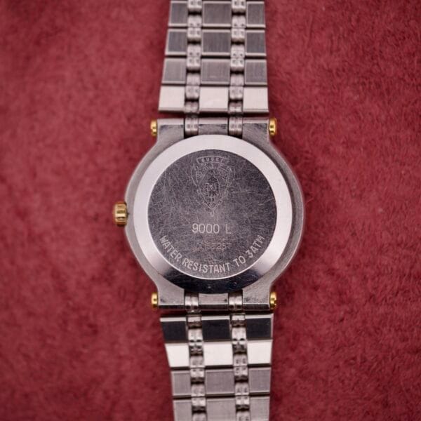 Back of a Gucci 9000 Ladies Watch Black Slate Dial Two-Tone Quartz with "9000 L" engraved, resting on a textured red surface—an elegant timepiece celebrated for its sophisticated black slate dial.