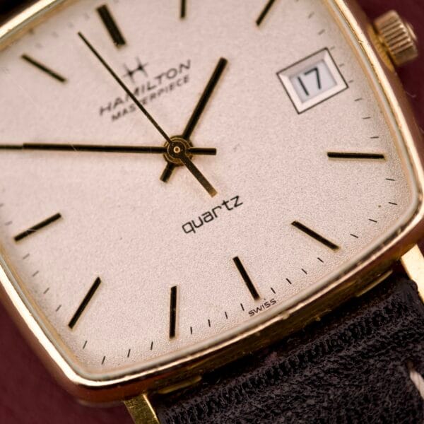 Close-up of a Hamilton Masterpiece Ref. 9116 10K Gold Filled TV Case Quartz, featuring black hands and a date window showing 17.